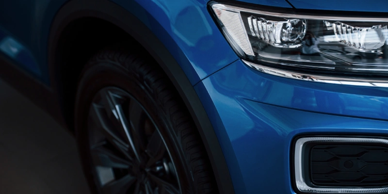 Front part of brand new modern blue car. Parked at showroom. Reflection in the headlights